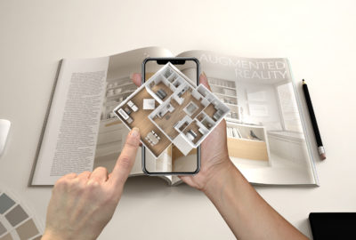 Augmented reality concept. Hand holding smartphone with AR application used to simulate 3d pop-up interactive house maps to life